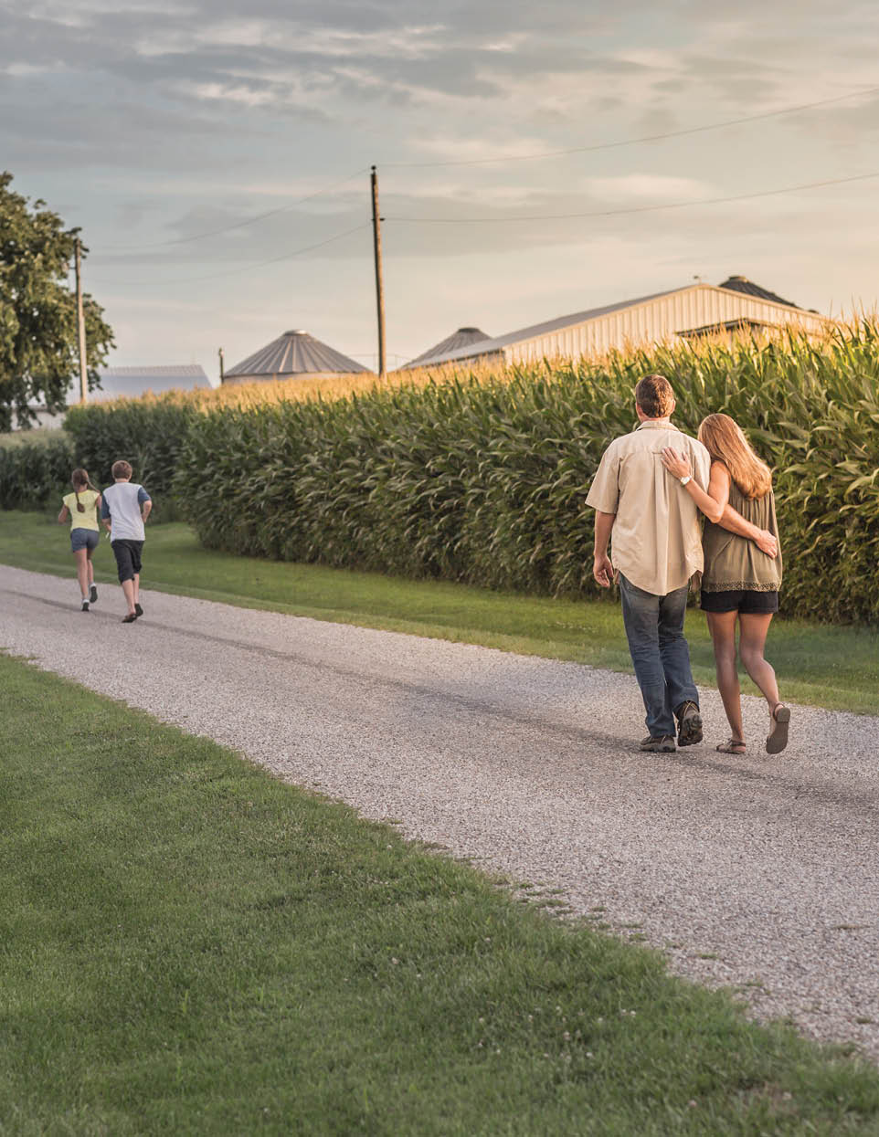 Caucasian family walking on dirt path by corn field
